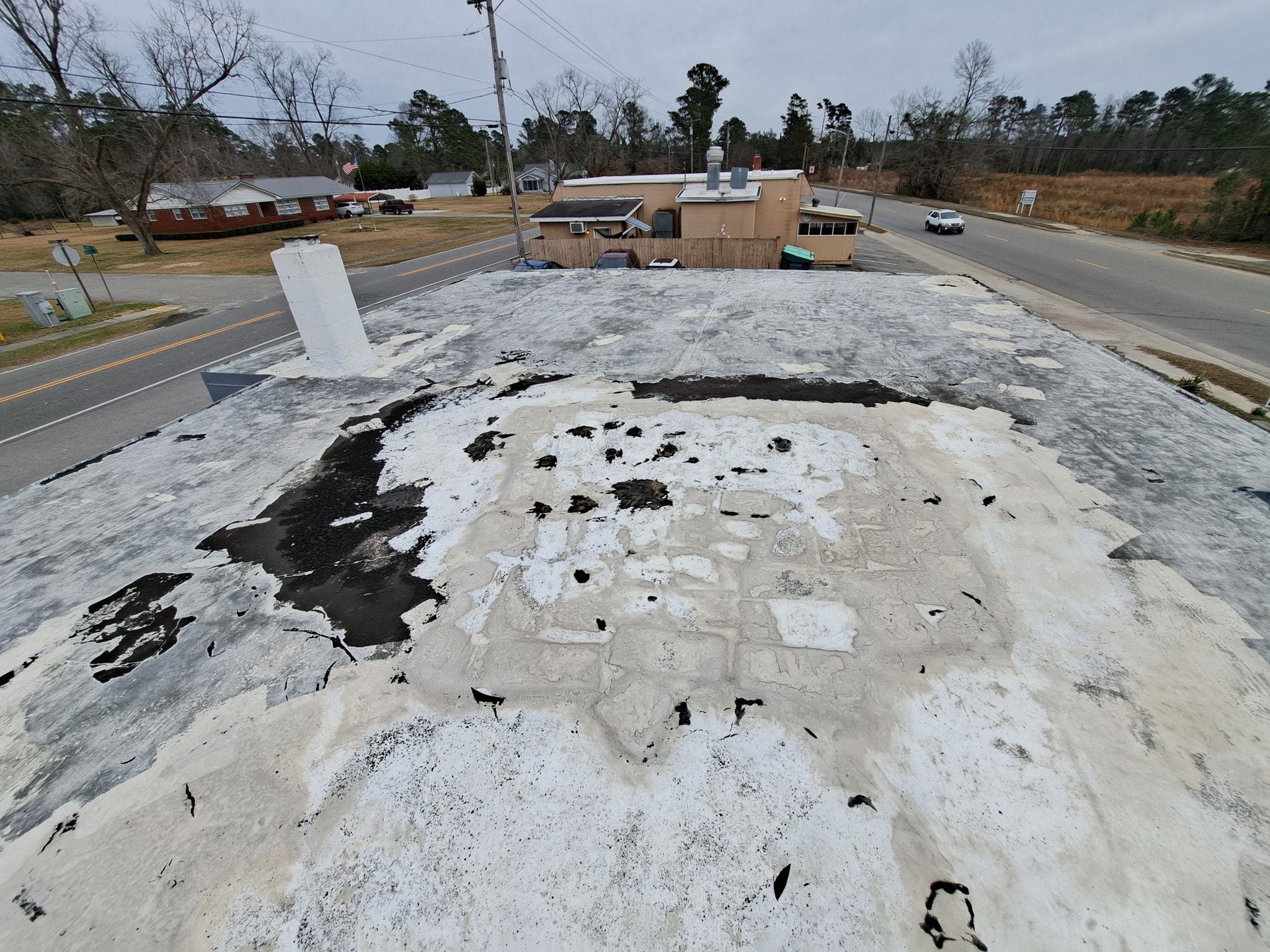 Little River Cafe roof before coating — crew member inspecting damaged surface