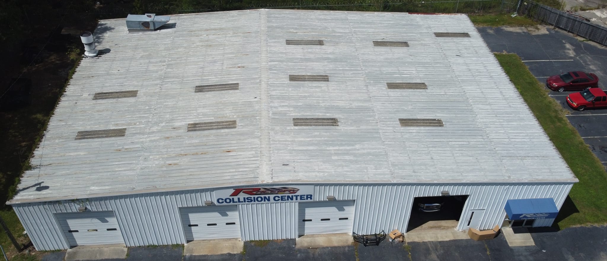 Raceway Collision Center roof before coating — weathered metal surface with garage doors visible